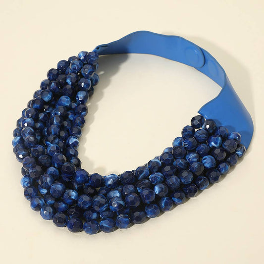 Blue beaded necklace with magnetic closure on a beige background