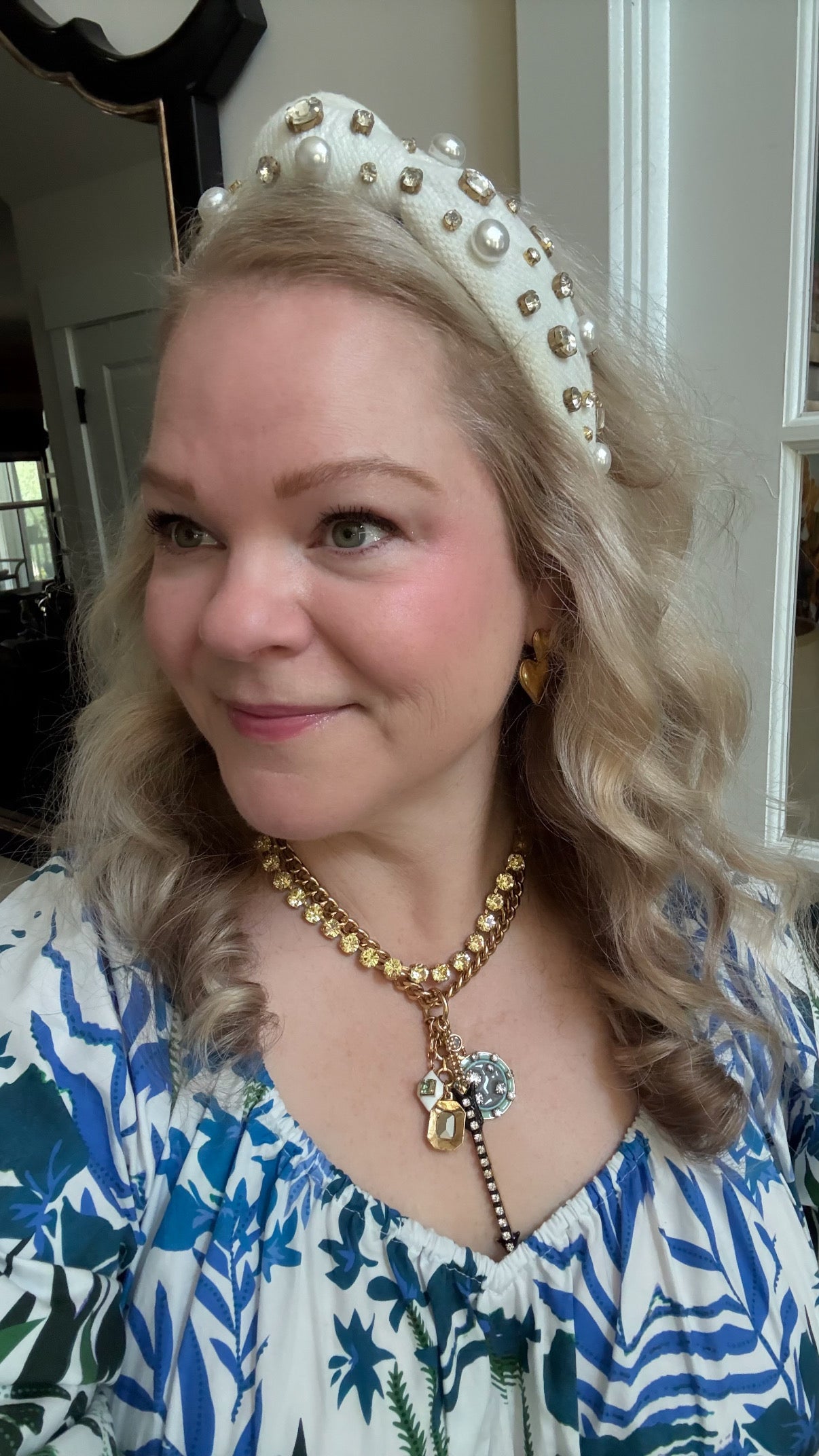 Woman wearing yellow crystal layering necklace with a charm pendant necklace and a blue floral dress