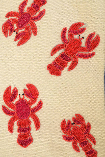 close up view of lobster beaded tote bag showing red beaded detailing of the lobsters on a cream canvas fabric