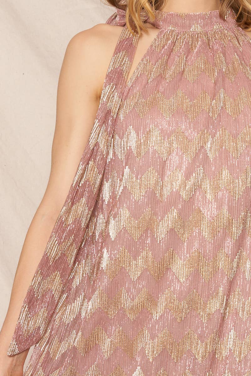 A woman wearing a metallic chevron print halter neck maxi dress with sleeveless design, standing in front of an ivory background