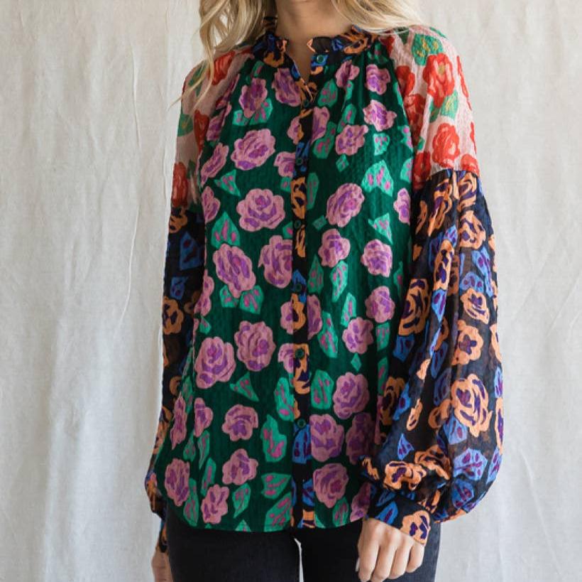 woman wearing a colorful floral print blouse against an ivory background