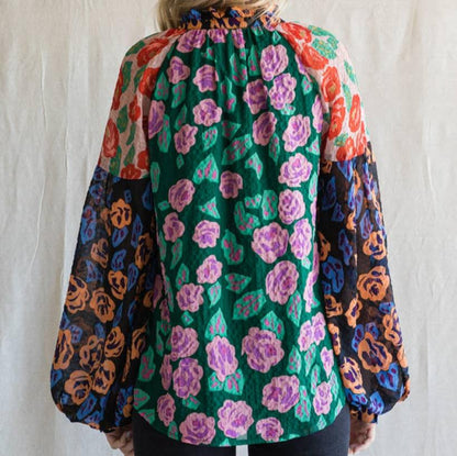 back view of a woman wearing a floral print blouse against an ivory background