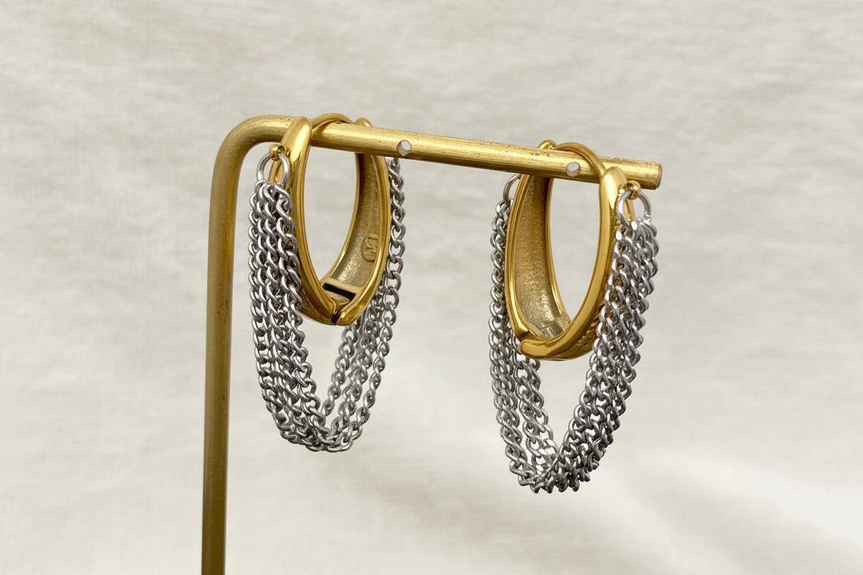 Gold and silver chain hoop earrings on a stand with a neutral background
