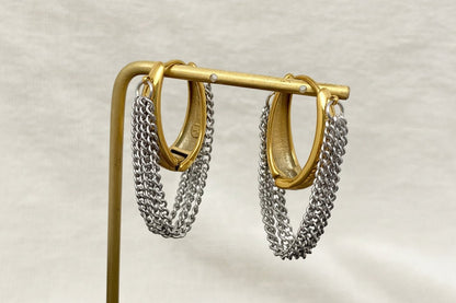 Gold and silver chain hoop earrings on a stand with a neutral background