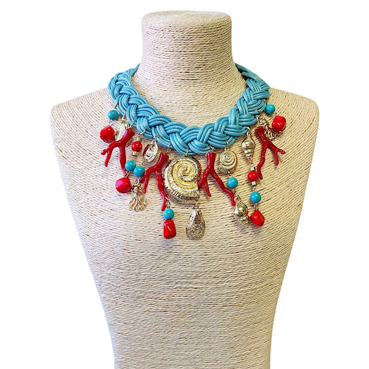 turquoise, red, and gold charms on a turquoise braided necklace on a mannequin.