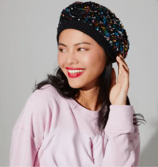 Woman wearing multicolor sequin beret styled to the side with a casual outfit