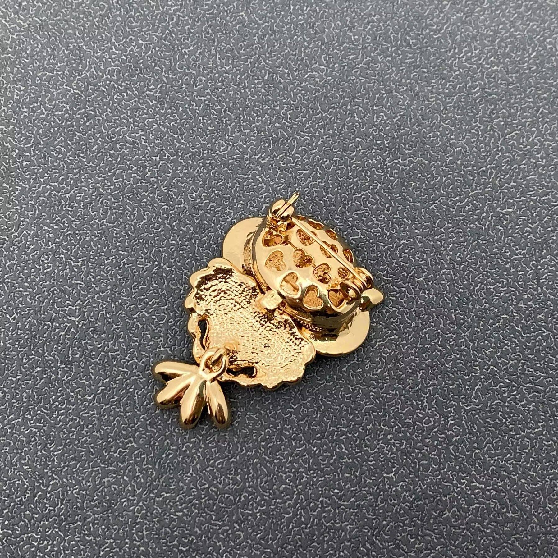 Gold charm shaped like a castle on a textured gray background