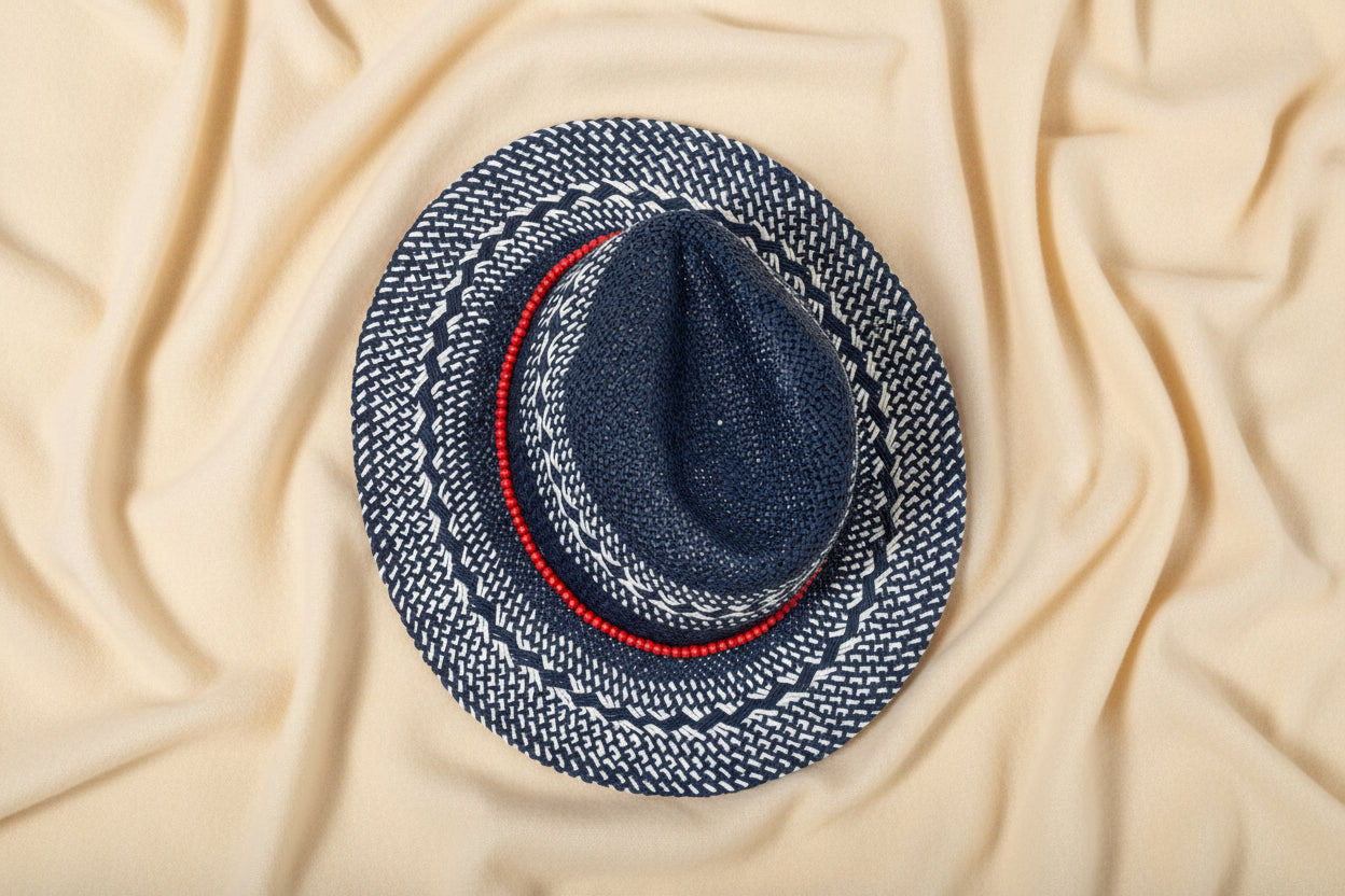 Blue and white patterned hat with a red band on an ivory fabric background