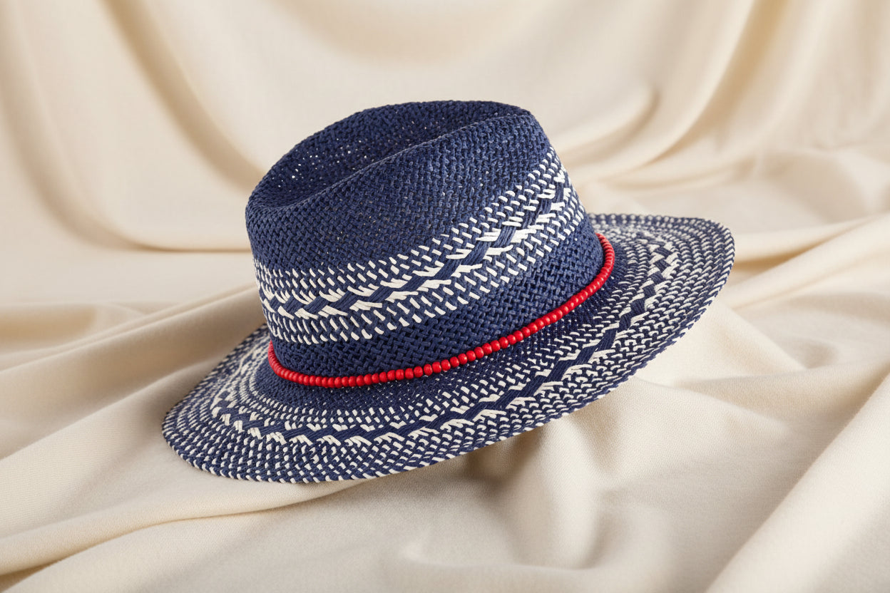 Navy and white woven sun hat with red beaded trim against an ivory fabric background