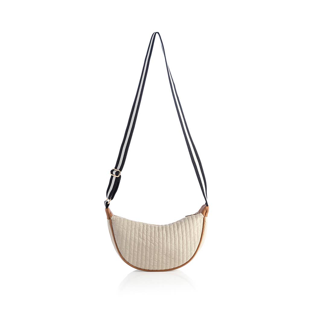 A quilted cross body bag with a striped black strap and a beige body, displayed against a white background.