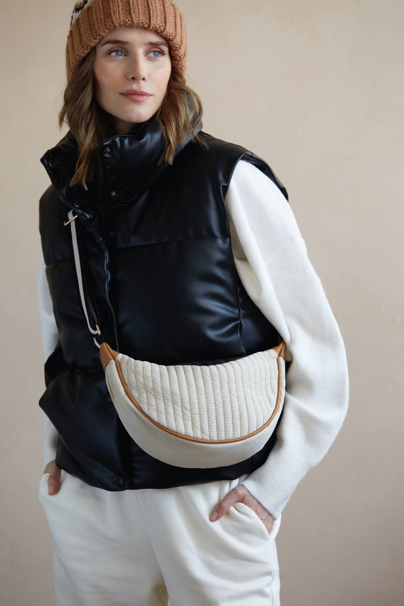 Woman in a black puffer vest wearing cream quilted nylon sling bag crossbody style