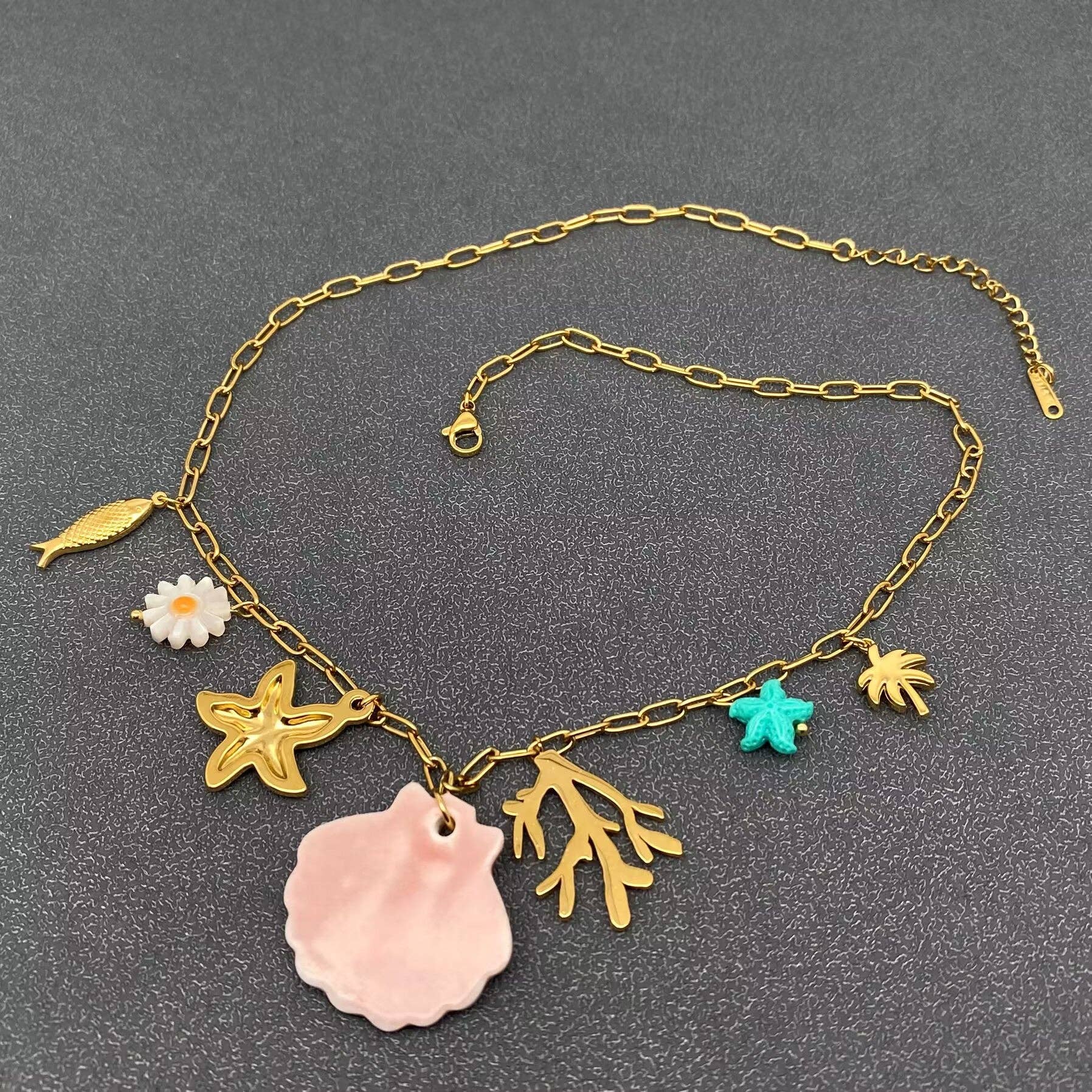back view of ocean themed multi charms necklace against a grey background