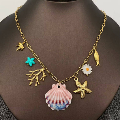 ocean themed multi charm necklace with 7 charms and central ceramic hand painted clam shell on gold chain against a black necklace stand.