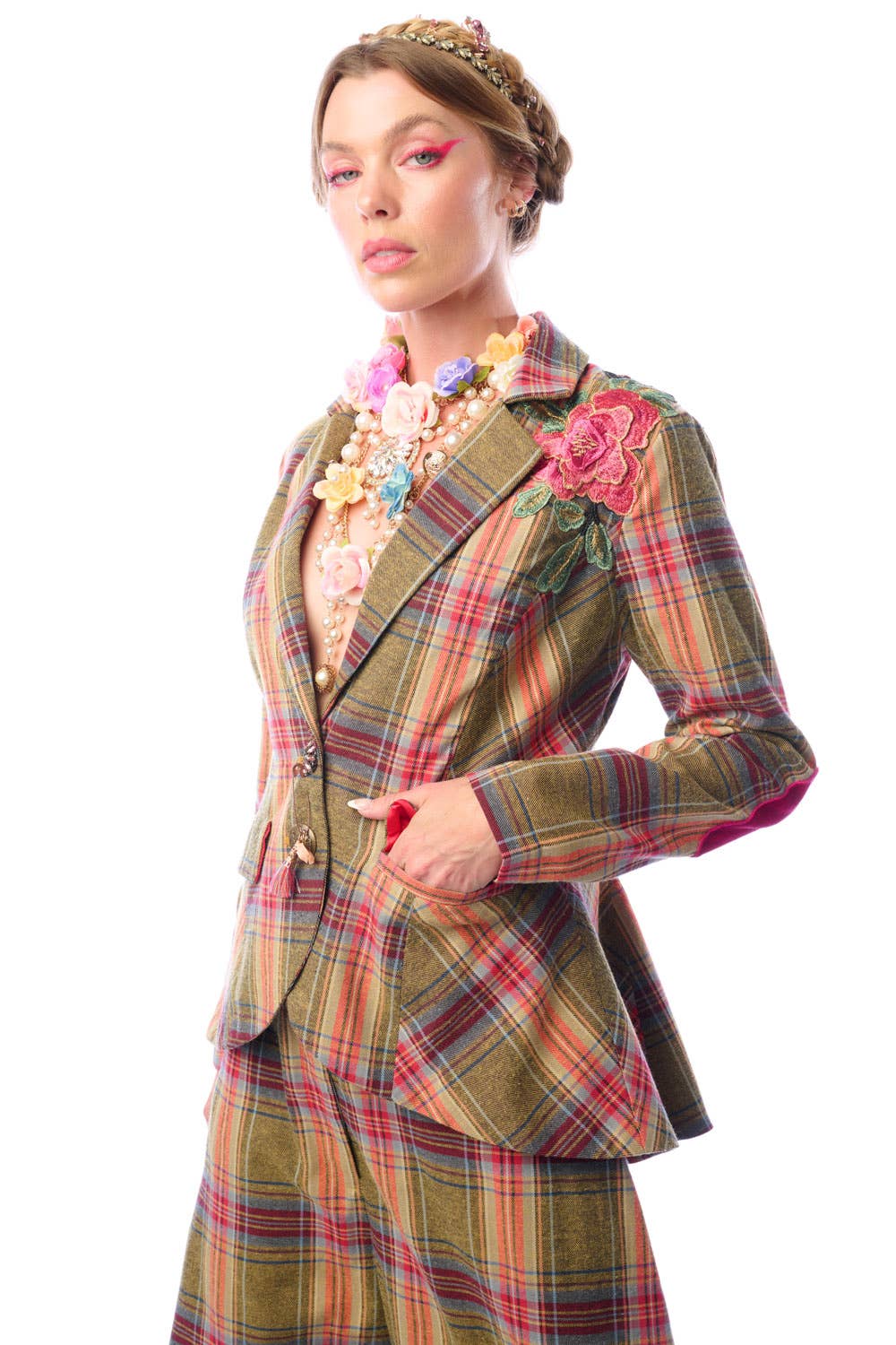 Woman wearing a plaid suit with floral accessories on a white background