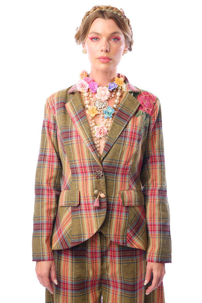 Woman wearing a colorful plaid suit with floral accessories on a white background
