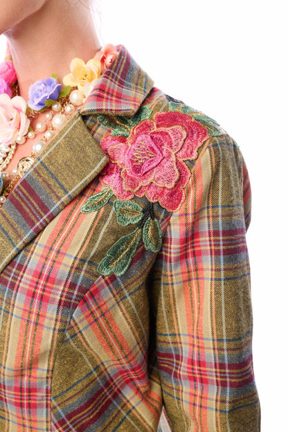 Up close view of plaid jacket with floral embroidery and colorful jewelry on a white background