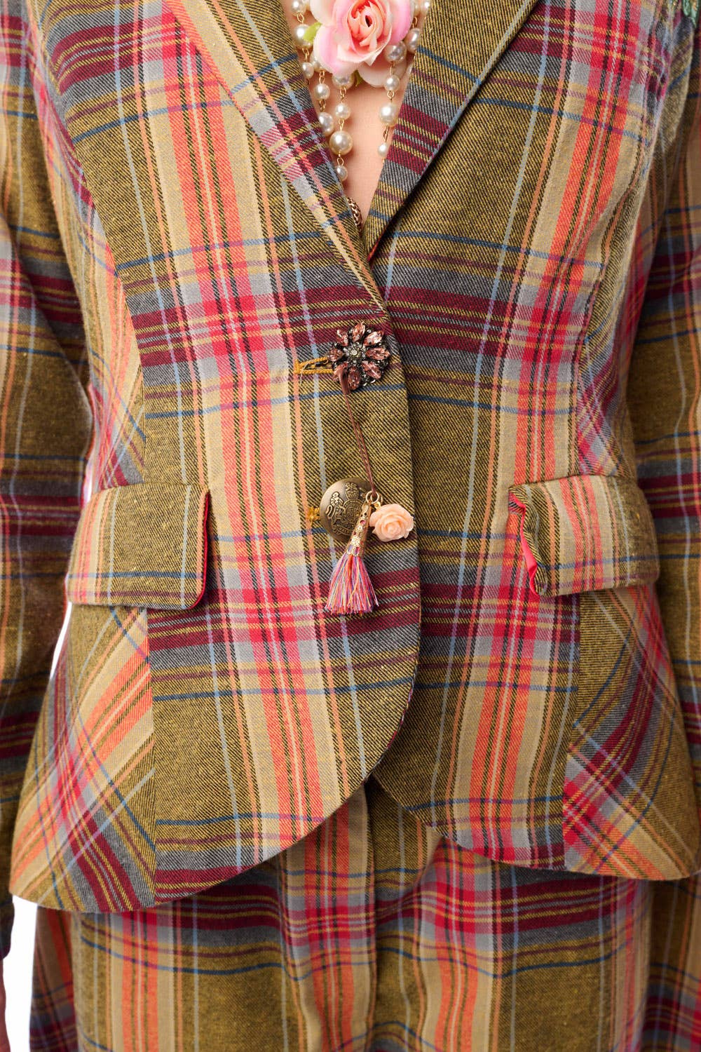 Up close view of plaid suit jacket with floral details to show crystal button detailing on a person