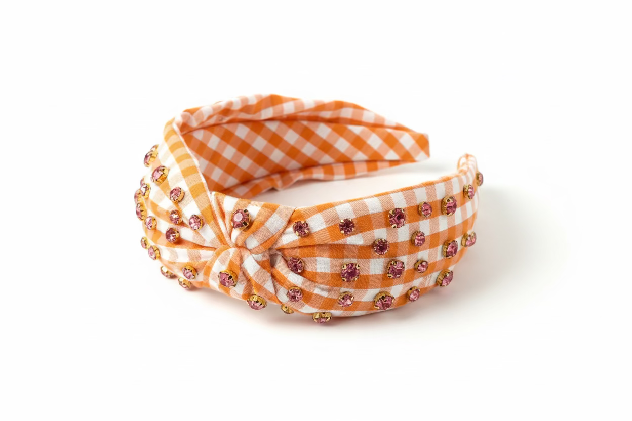 Orange and white gingham headband with pink rhinestones on a white background