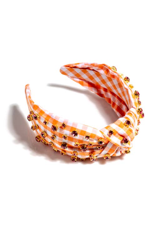An orange and white gingham knotted headband with multicolored rhinestone details against a white background
