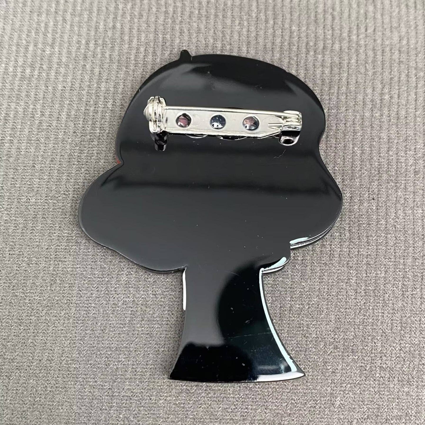 Back view of woman acrylic brooch on a textured gray background