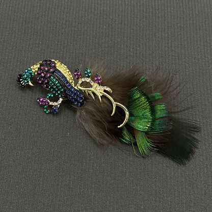 Decorative peacock brooch with feathers and gemstones on a gray background