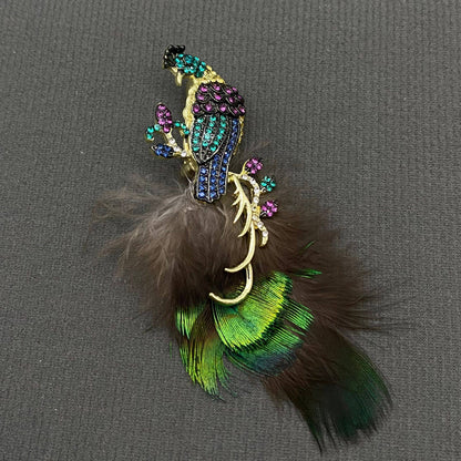 Decorative peacock brooch with feathers and gemstones on a gray background