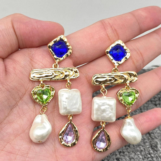 hand holding pearl and multi-colored glass inlaid stone earrings