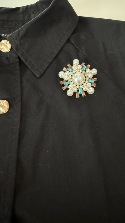 Black jacket with a decorative brooch featuring pearls and gemstones.