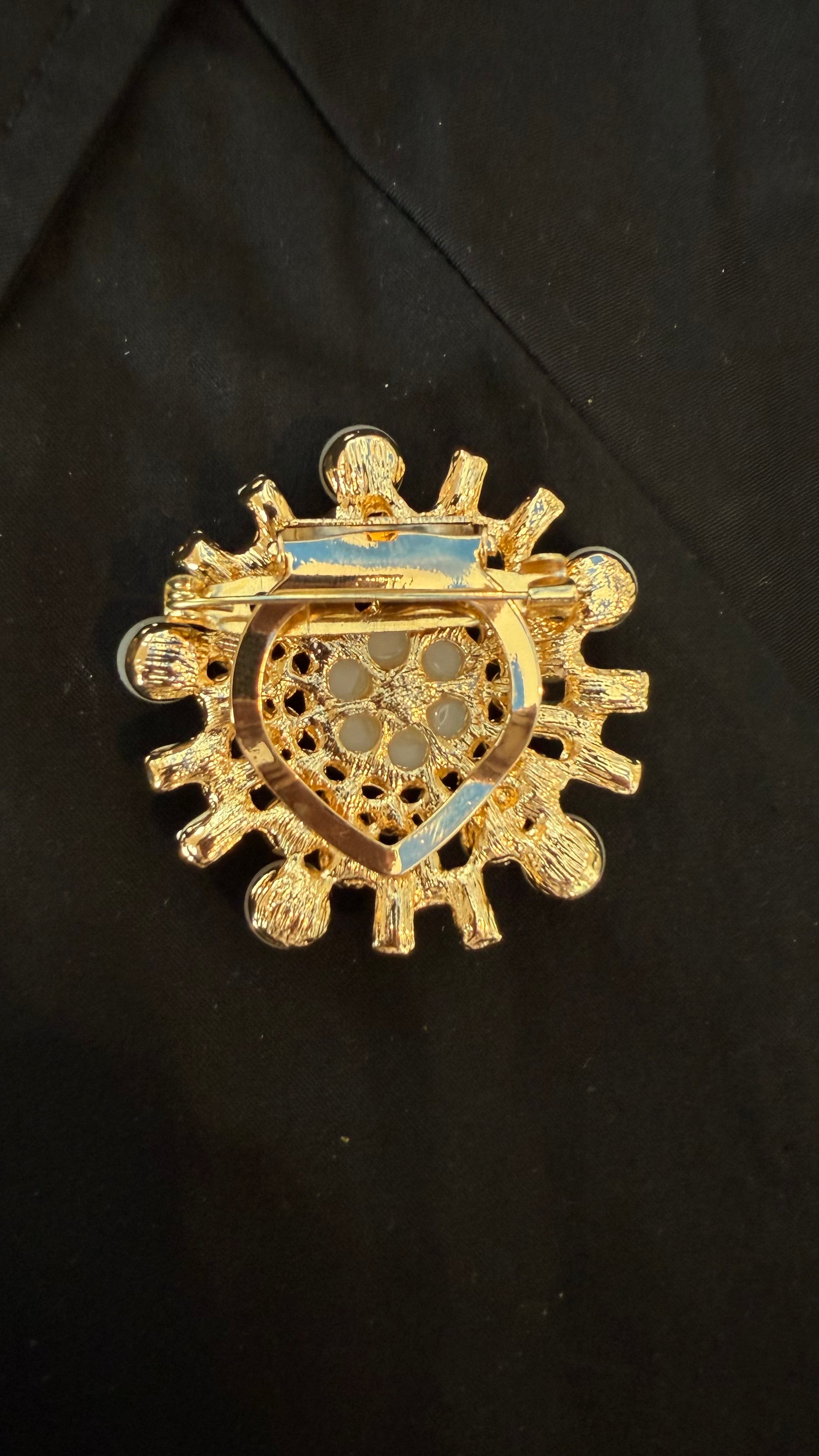 back view of brooch with intricate design on a black background