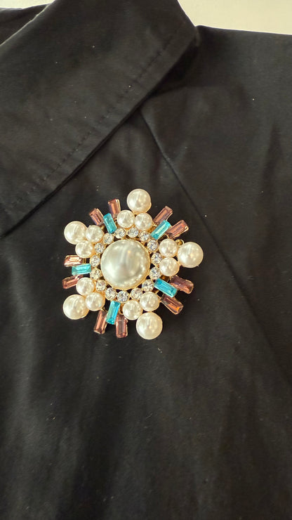 Decorative brooch with pearls and gemstones on a black jacket