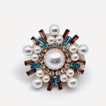 Decorative brooch with pearls and gemstones on a white background