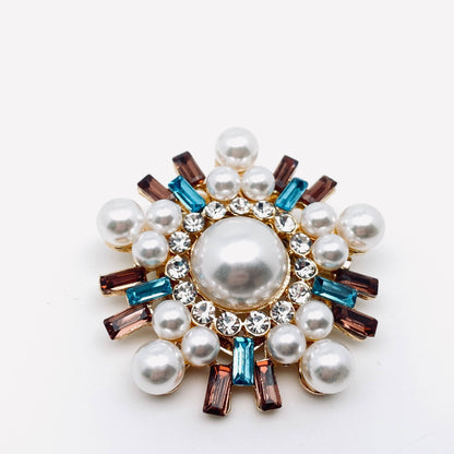 Decorative brooch with pearls and gemstones on a white background