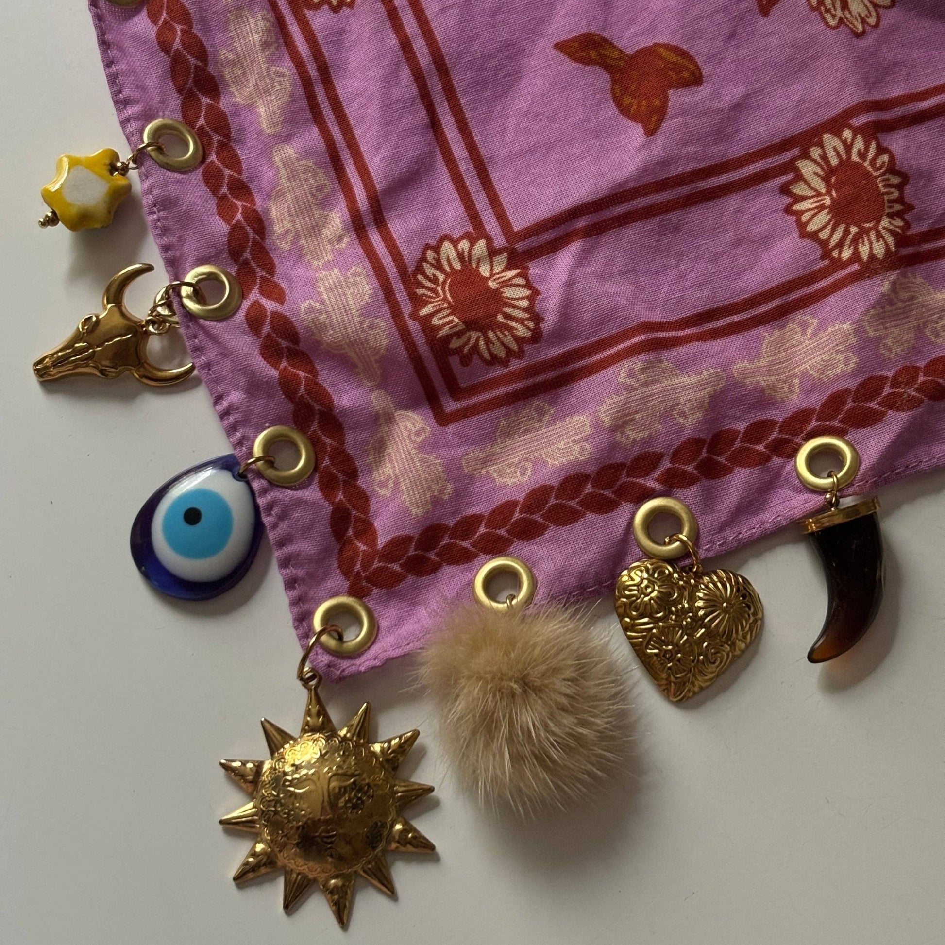 Pink fabric with gold and decorative charms on a white background