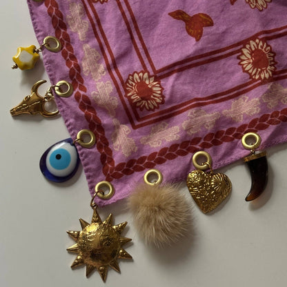 Pink fabric with gold and decorative charms on a white background