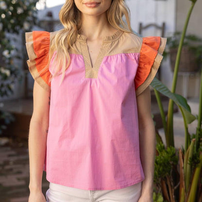 a woman wearing a pink colorblock short sleeve blouse outside