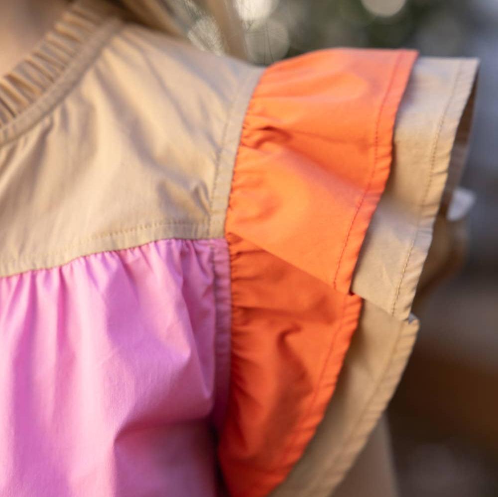 up close view of sleeve detail on a pink color block short sleeve blouse with a blurred background