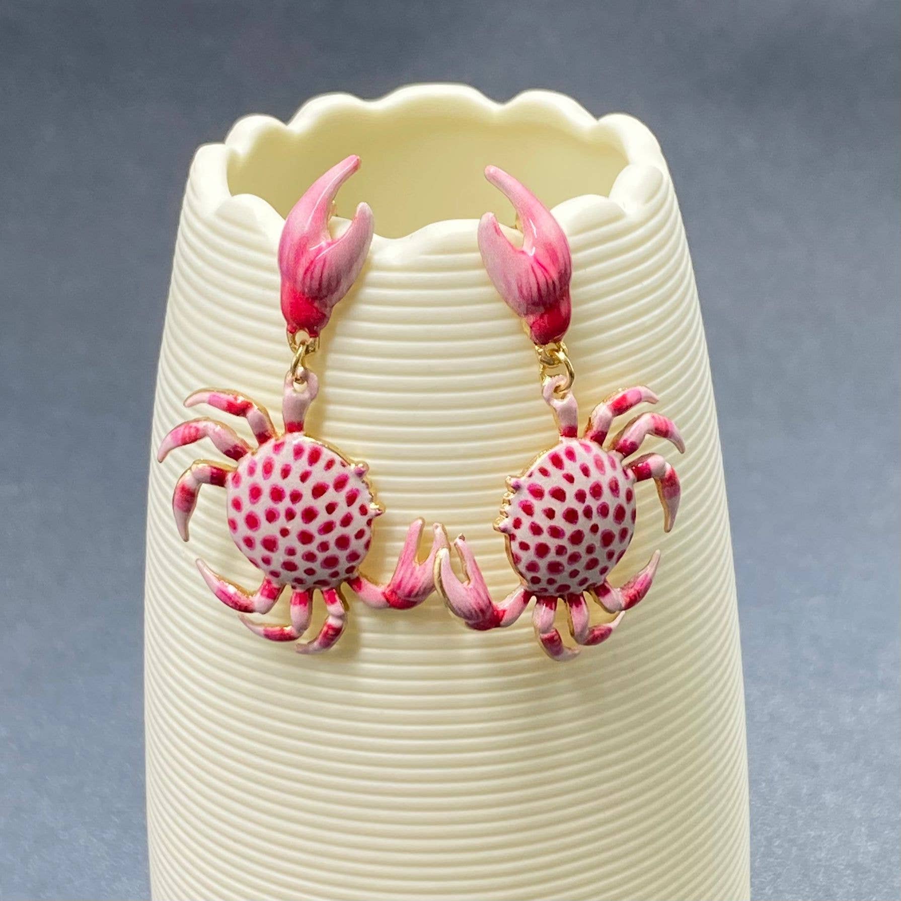a pair of pink and white enamel crab dangle earrings