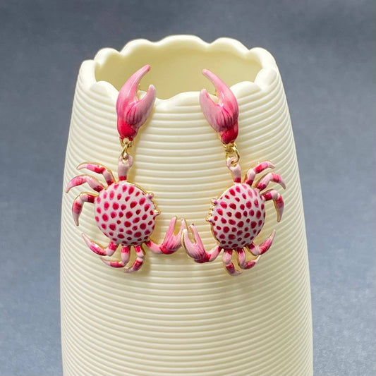 a pair of pink and white enamel crab dangle earrings