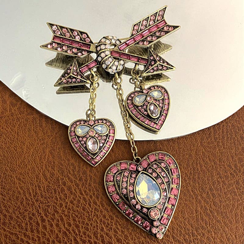 Decorative brooch with heart and arrow design on a leather and mirrored surface