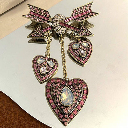 Decorative brooch with heart and bow design on a mirrored background