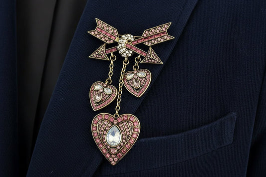 Decorative heart and arrows shaped brooch with pink gemstones on a navy corduroy blazer lapel
