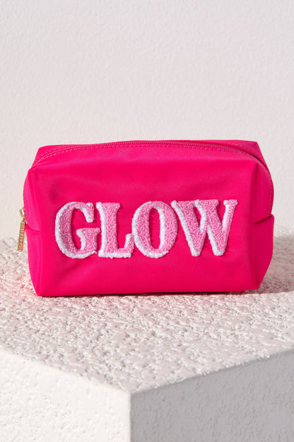Pink cosmetic bag with 'GLOW' text on an ivory textured surface