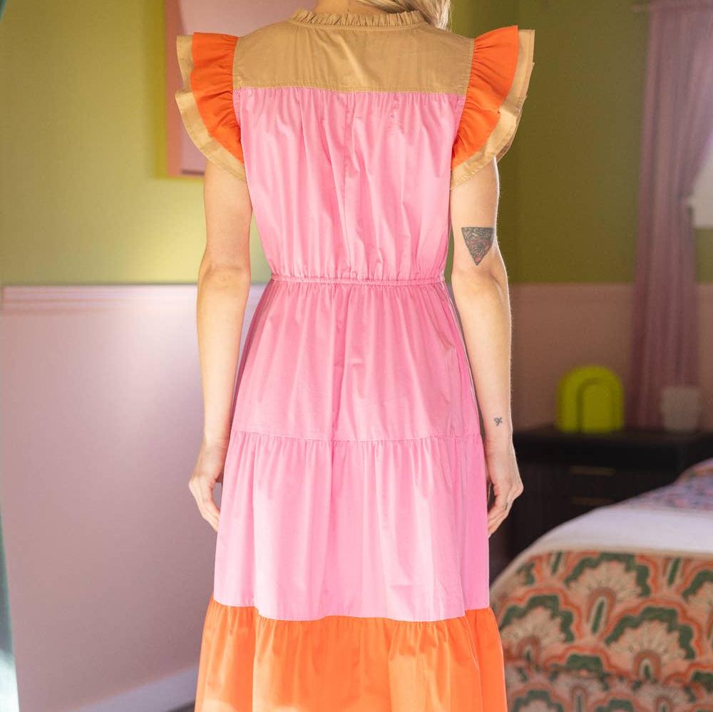 the back view of a woman wearing a pink and orange short sleeve dress