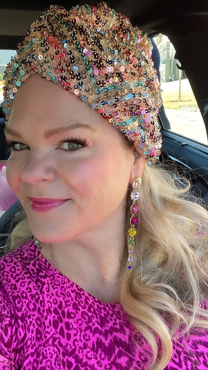 a woman with blonde hair and pink dress and sequin turban wearing rainbow crystal drop earrings