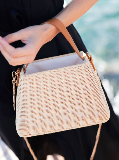 Woven handbag held by a person with a blurred natural background