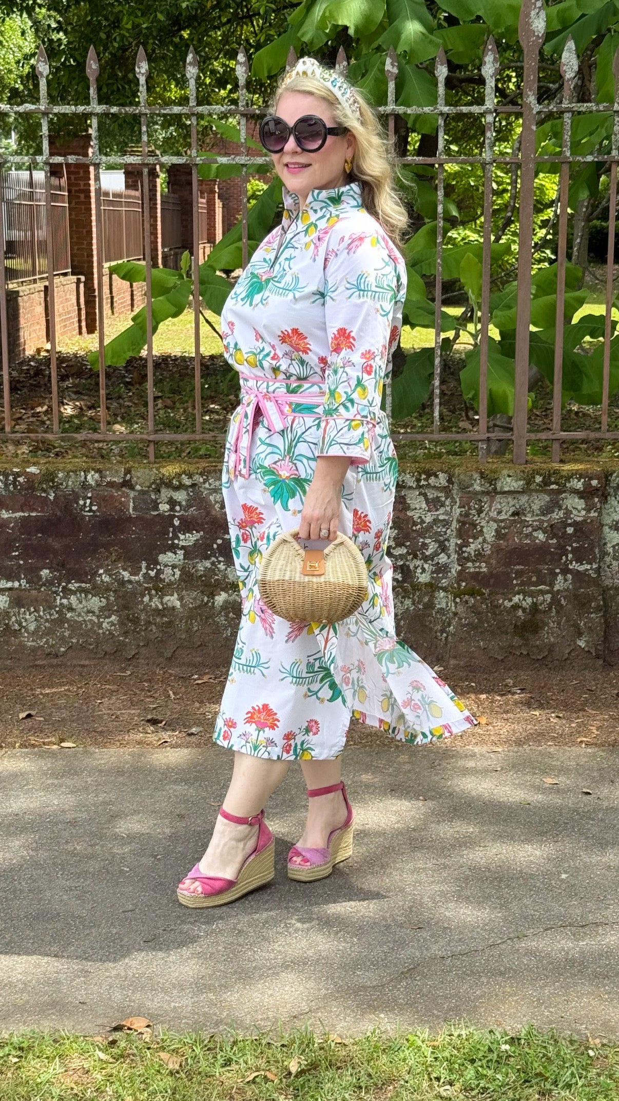 Woman in floral dress carrying rattan and woven crossbody purse — lifestyle view showing bag scale and crossbody styling