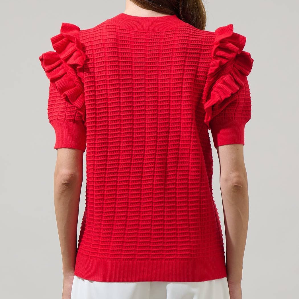 a woman wearing a red textured top with ruffled sleeves on a plain background