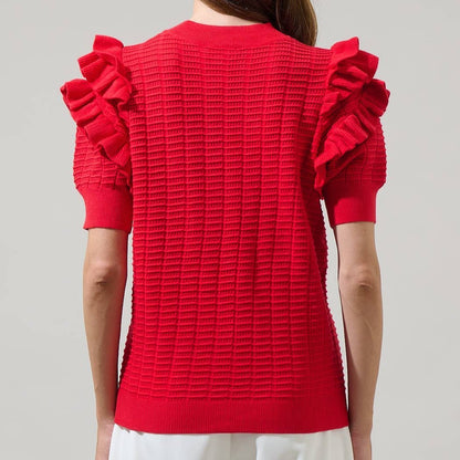 a woman wearing a red textured top with ruffled sleeves on a plain background