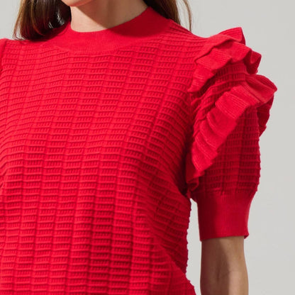 Red textured sweater with ruffled sleeves on a neutral background