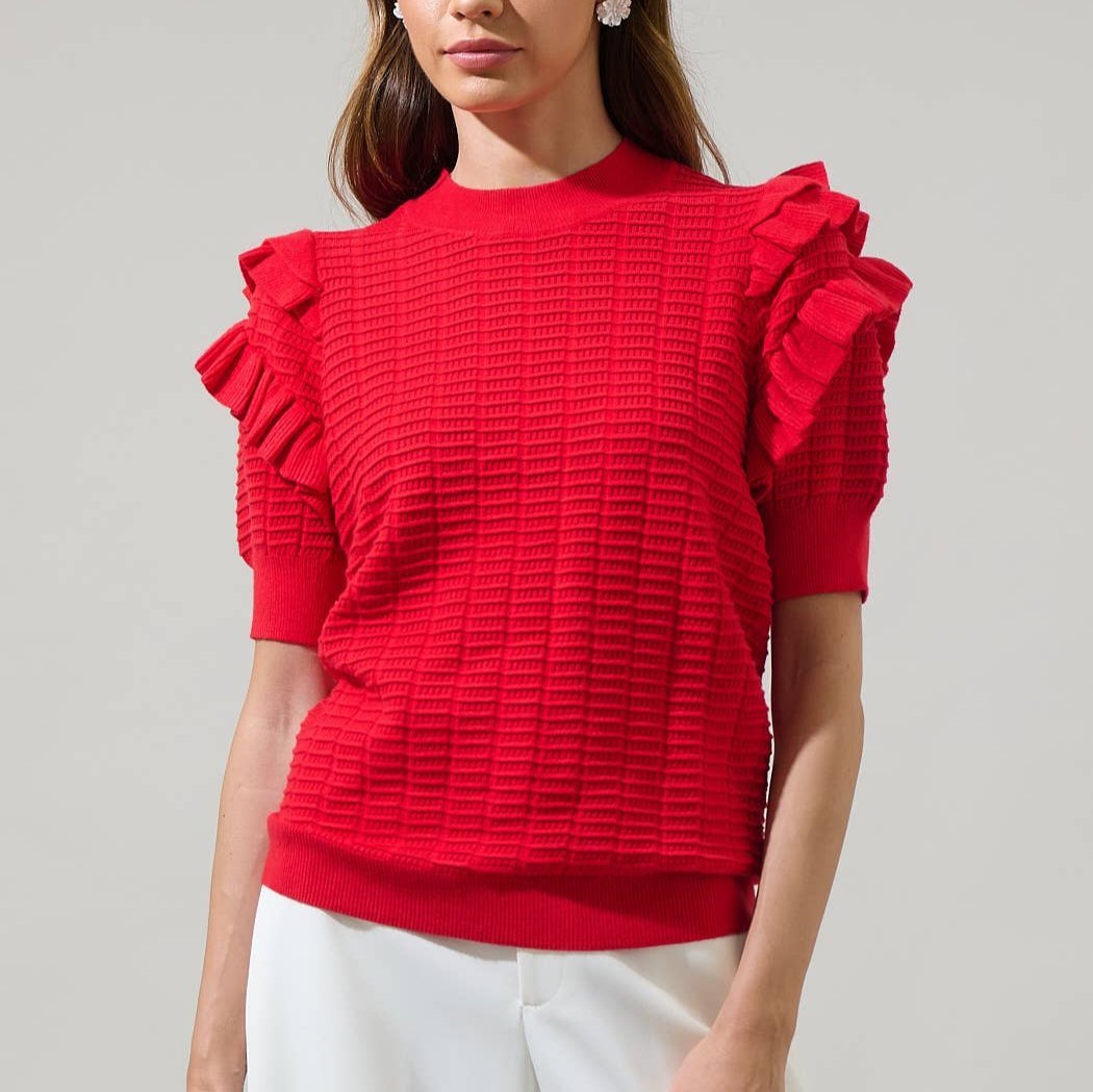 Red textured blouse with ruffled sleeves worn by a person on a gray background